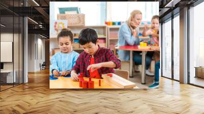 Selective focus of kids playing games with children and teacher at background in montessori school Wall mural