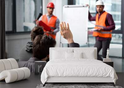 Selective focus of man raising hand near handsome firemen in helmets standing near white board Wall mural