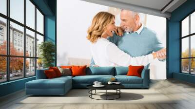 selective focus of mature couple looking at each other while dancing at home Wall mural