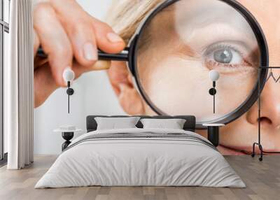 selective focus of mature woman looking at camera and holding loupe isolated on grey Wall mural