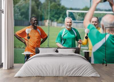 selective focus of multiracial old friends with football ball on green field Wall mural