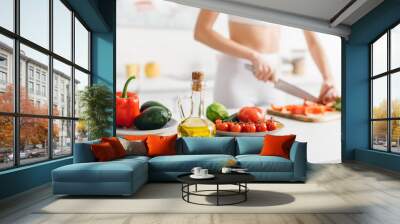 Selective focus of organic vegetables and avocado near sportswoman cooking salad on kitchen table Wall mural