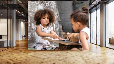 selective focus of poor african american kid writing in notebook near brother outside Wall mural