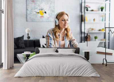 Selective focus of pretty woman working with laptop and headphones Wall mural