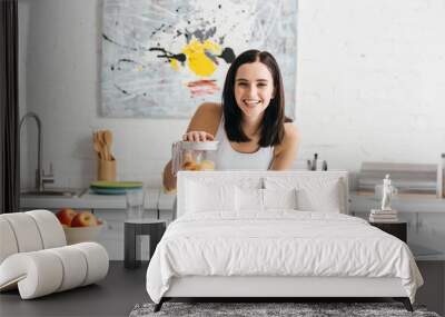 Selective focus of smiling sportswoman preparing smoothie near measuring tape and fruits on kitchen table, calorie counting diet Wall mural