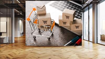 selective focus of toy shopping cart with small carton boxes near laptop, e-commerce concept Wall mural