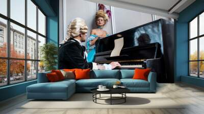 selective focus of victorian woman looking at man in wig playing piano Wall mural