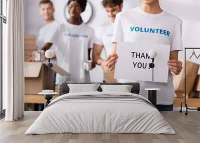 Selective focus of volunteer holding card with thank you lettering near donations and multiethnic people Wall mural