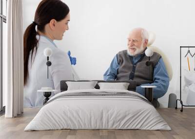 senior patient in dental chair taking consultation from smiling doctor with tablet in hands. Wall mural