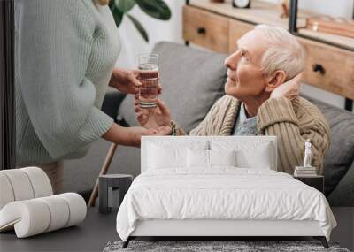 senior woman helping to old man with walking stick and giving pills Wall mural