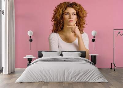 serious and pensive redhead woman holding hand near face while looking away isolated on pink Wall mural