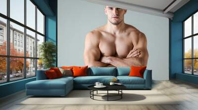 sexy muscular bodybuilder with bare torso posing with crossed arms isolated on grey Wall mural