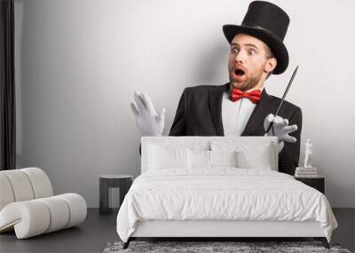 shocked magician with open mouth holding wand, isolated on grey Wall mural