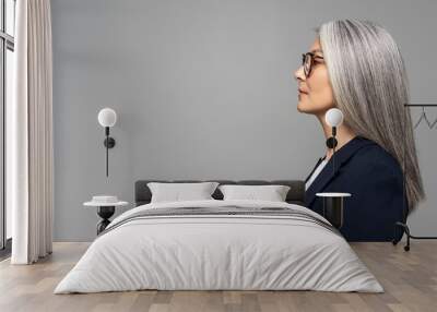 side view of beautiful asian businesswoman with grey hair in eyeglasses isolated on grey Wall mural