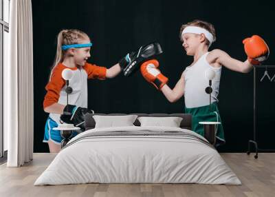 Side view of boy and girl in sportswear boxing isolated on black, activities for children concept Wall mural