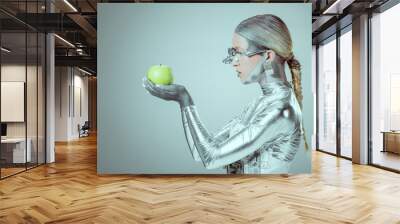 side view of cyborg holding and examining green apple isolated on grey, future technology concept Wall mural