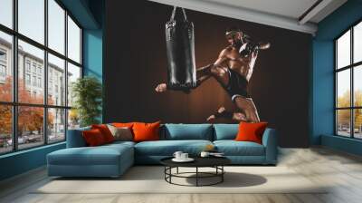 side view of focused muay thai fighter practicing kick on punching bag, action sport concept Wall mural