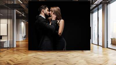 side view of handsome man touching face of attractive woman in dress isolated on black Wall mural