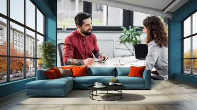 smiling account managers sitting at table and talking in office Wall mural