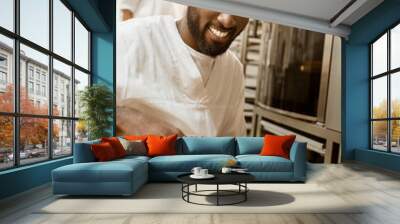 smiling african american baker with tray of fresh loaves of bread on baking manufacture Wall mural