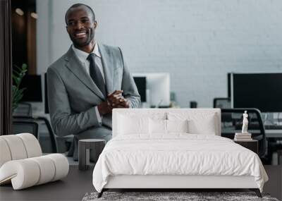 smiling african american businessman sitting on table in office Wall mural