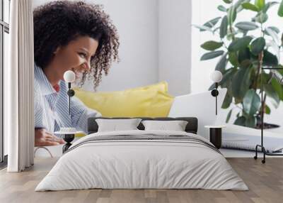 Smiling african american freelancer using laptop near credit card and notebook, banner Wall mural