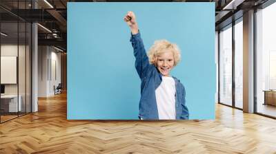 smiling and cute kid showing yes gesture and looking at camera isolated on blue Wall mural