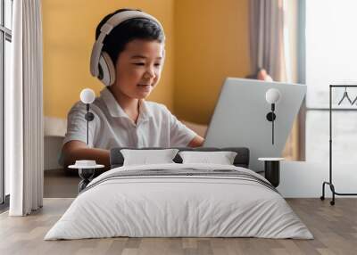 smiling asian boy studying online with laptop and headphones at home during quarantine Wall mural