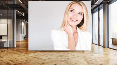 smiling beautiful young blonde woman in total white outfit looking away isolated on grey Wall mural