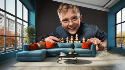 smiling little boy in eyeglasses playing chess isolated on grey background Wall mural