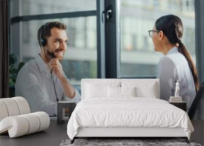 smiling male translator working online with laptop and headset on meeting with businesswoman Wall mural