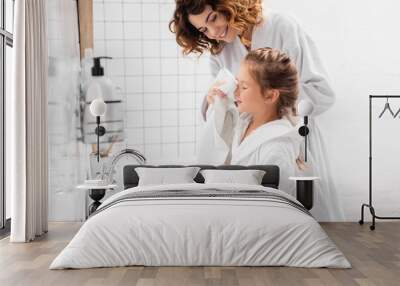 Smiling mother drying face of daughter with towel in bathroom Wall mural