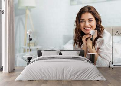 smiling woman lying in bed and looking at camera at morning Wall mural