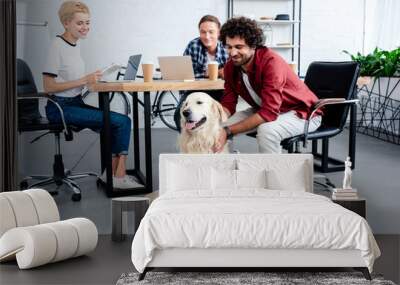 smiling young business people looking at dog while working in office Wall mural