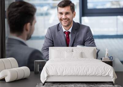 smiling young businessman looking at manager with clipboard at job interview, business concept Wall mural