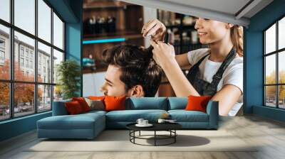 smiling young hairdresser cutting hair to handsome happy man in beauty salon Wall mural