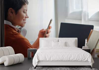 smiling young student looking at textbook with phone in hands and laptop on table, studying, banner Wall mural