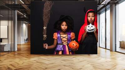 spooky african american kids in halloween costumes holding pumpkins isolated on black Wall mural