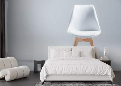 Studio shot of stylish chair with white top and light wooden legs standing on white Wall mural