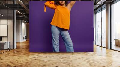 Stylish African American woman poses against vibrant backdrop in orange shirt. Wall mural