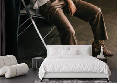 stylish blonde woman in white blouse and boots with snakeskin print sitting on chair near curtain on brown Wall mural