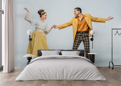 Stylish dancers holding hands while dancing boogie-woogie on grey background Wall mural