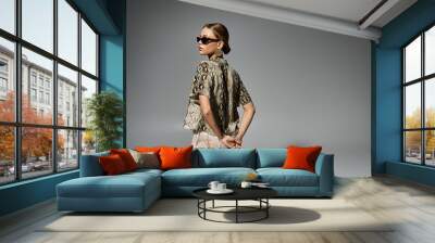 Stylish woman sporting sunglasses and a trendy snakeskin shirt. Wall mural