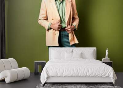 Stylish young African American man in a suit and sunglasses stands confidently in front of a vibrant green wall. Wall mural