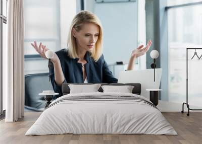 surprised businesswoman gesturing with hands and lookng at laptop in office Wall mural