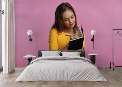 teenage girl writing in notebook and pen isolated on pink Wall mural