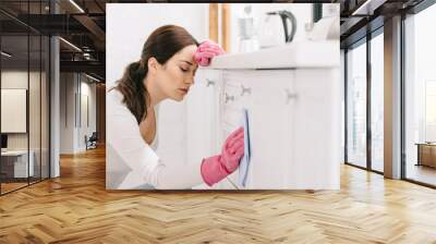 tired housewife with closed eyes washing kitchen furniture with rag Wall mural