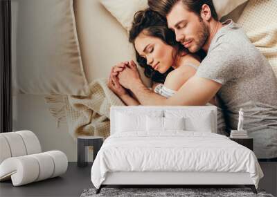 Top view of beautiful happy young couple hugging while sleeping on bed Wall mural