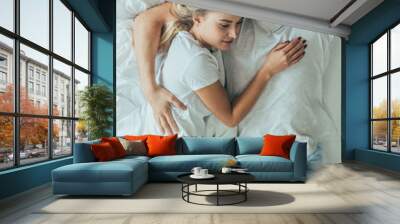 top view of beautiful young couple sleeping together and embracing in bed at home Wall mural