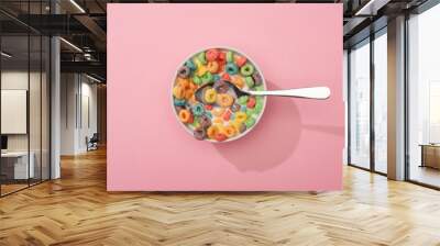 top view of bright colorful breakfast cereal in bowl with spoon on pink background Wall mural